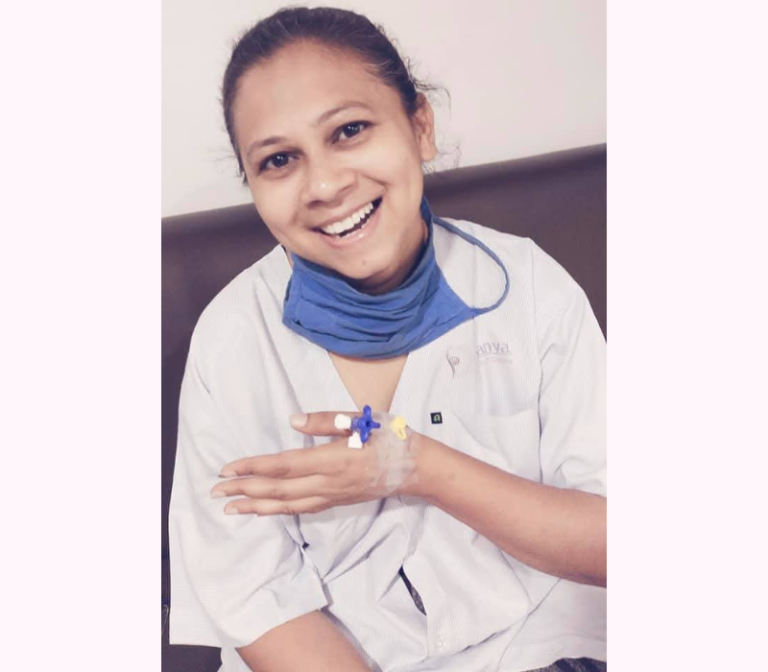 Archana Chauhan, hospitalized during her battle with cancer, wears white patient attire along with a hospital mask. Despite the challenges, her presence exudes resilience and quiet strength, embodying hope through adversity.